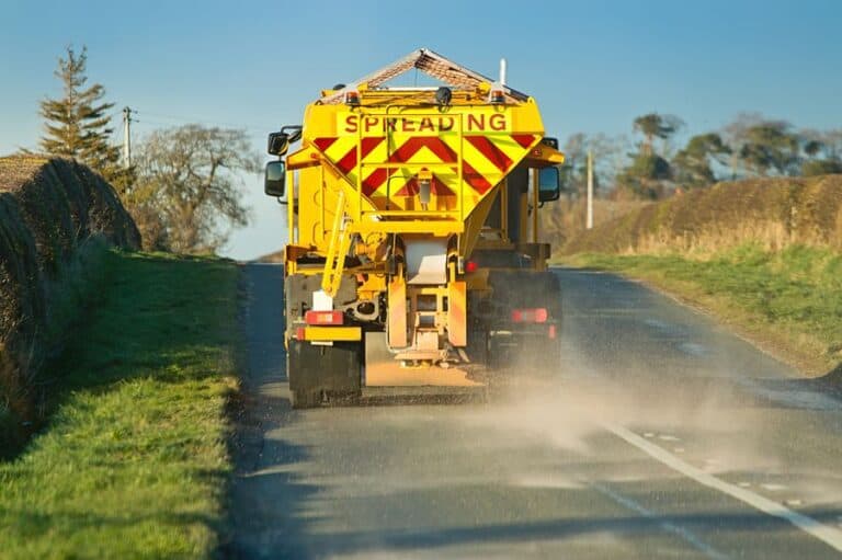 Gritter spreading rock salt on roads to help melt ice before the temperature drops.