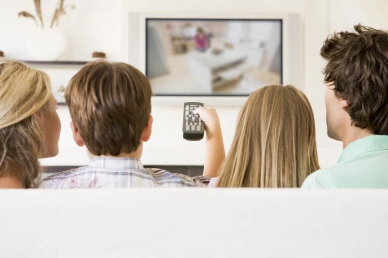 Family watching TV together, illustrating iconic TV moments that connect us, with a child holding the remote control, capturing the shared experience of television viewing.