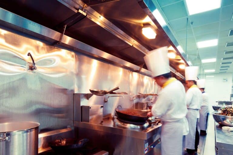 Professional chefs in white uniforms and hats working in a busy commercial kitchen